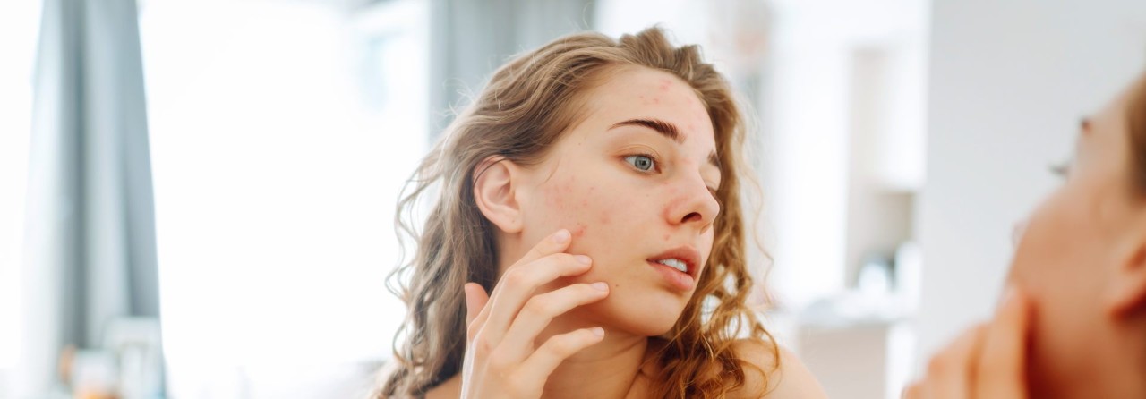 women-applying-face-product-to-face-in-mirror